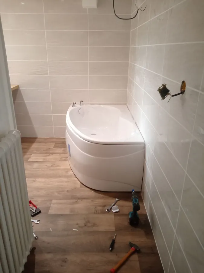 Salle de bain rénovée à Ormes — baignoire d'angle, faïence beige, sol imitation parquet